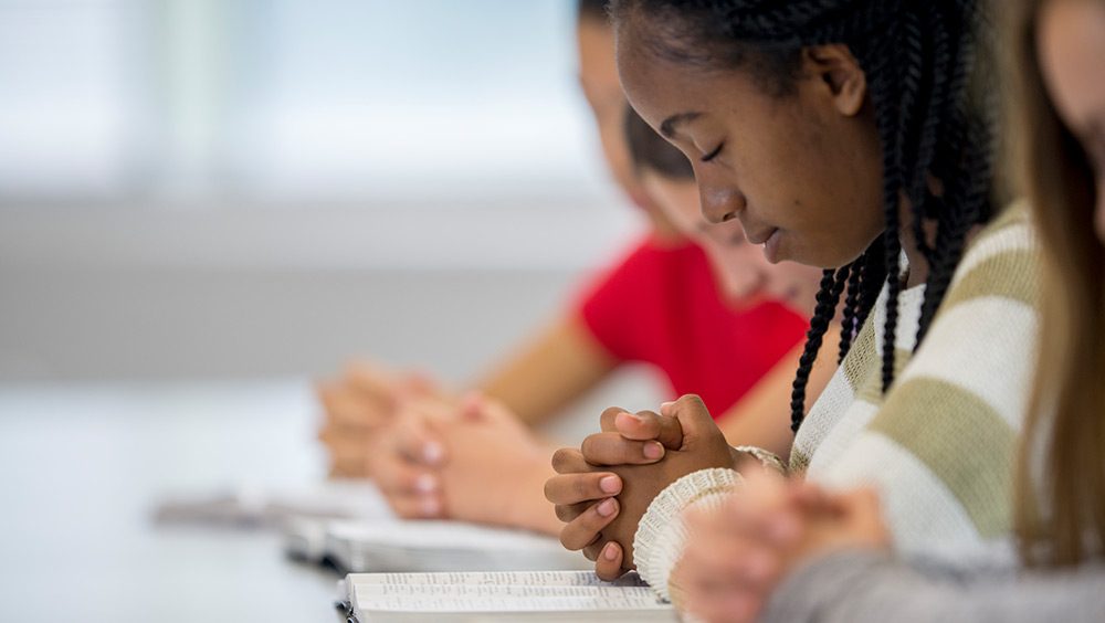 Students with hands clasped in prayer in school