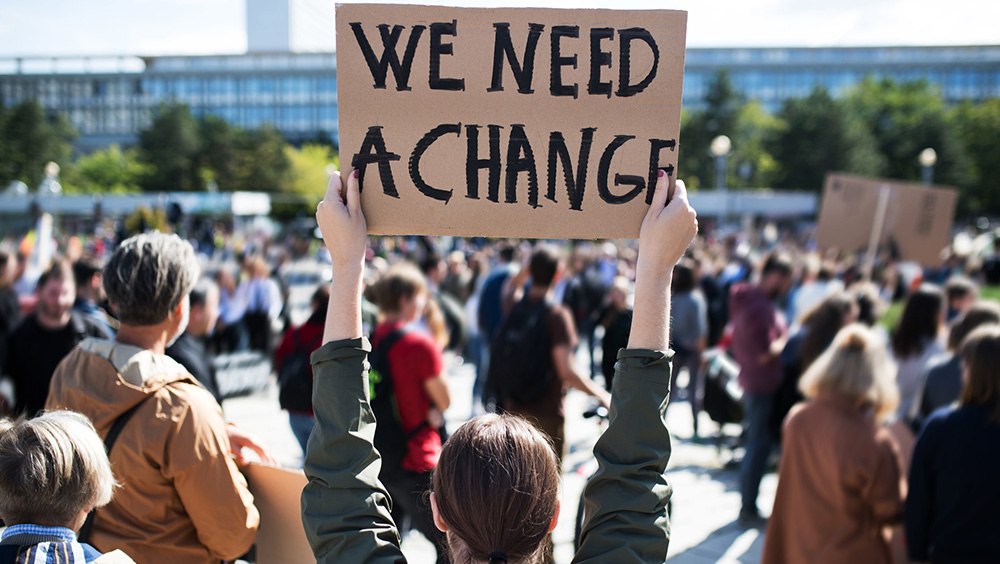 protester raising a sign representing the First Amendment freedom of assembly