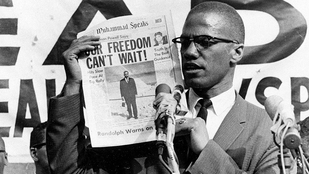 Malcolm X holds up a paper for the crowd to see during a 1963 rally in New York City.