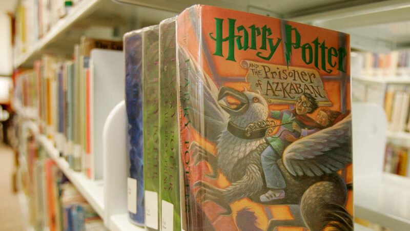Four Harry Potter books on a shelf in a library