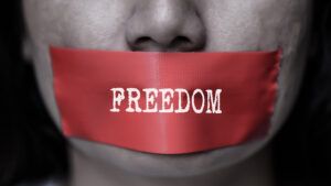 red tape over person's mouth with word freedom written on it