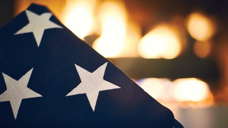 Stars of folded American flag in front of a fire
