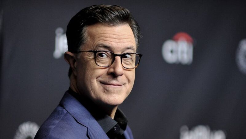 An image of Stephen Colbert looking slightly behind himself and smirking