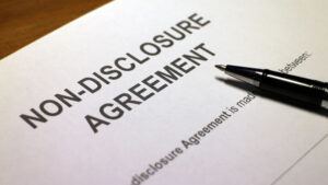 An image of a contract reading "non-disclosure agreement," with a pen resting on the paper
