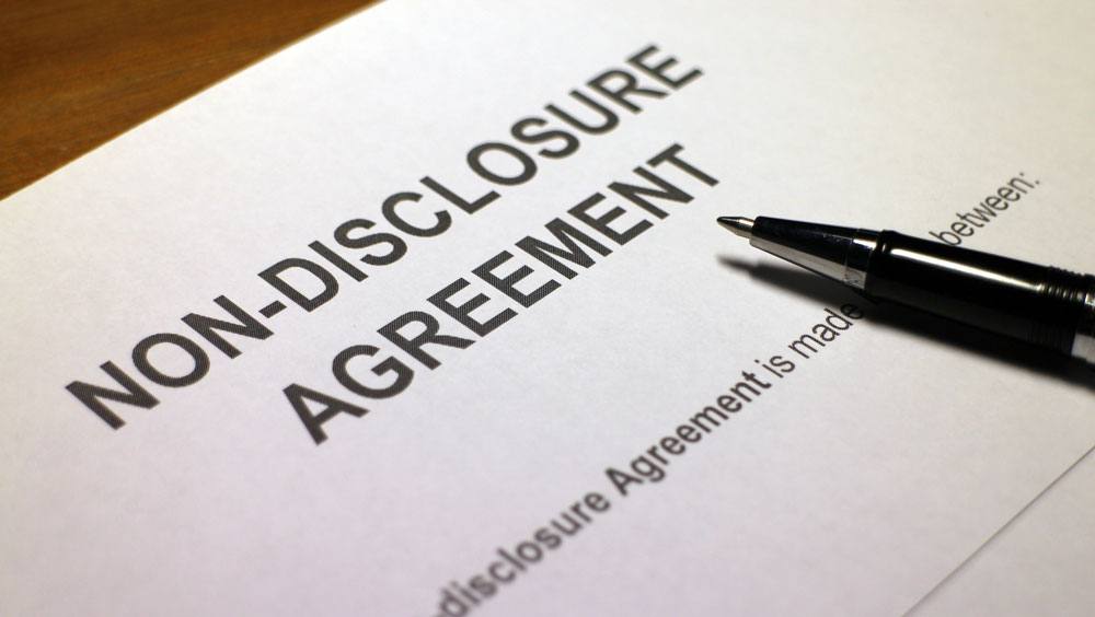 An image of a contract reading "non-disclosure agreement," with a pen resting on the paper
