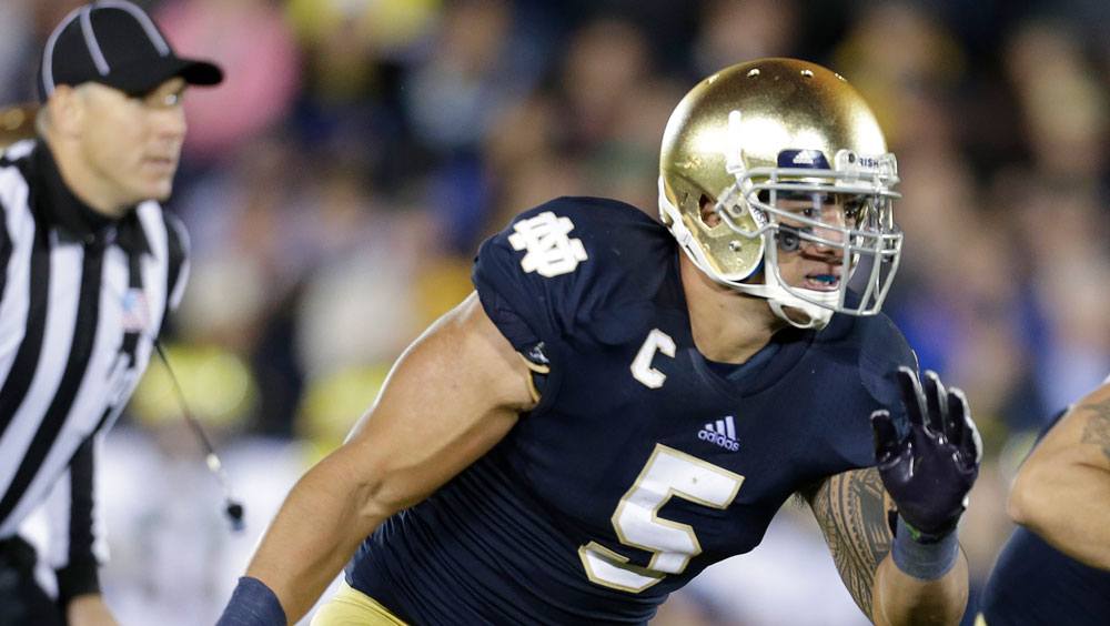 Photo shows a football player leaning forward as he runs on the field