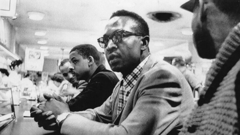 A black-and-white image of Black men sitting at a lunch counter