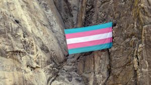 A view of a large, pink-and-blue transgender pride flag displayed on the El Capitan rock formation in Yosemite National Park.
