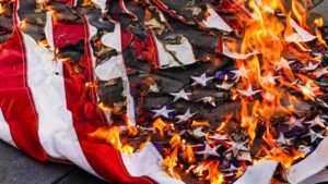 A U.S. flag burns as it sits on the ground
