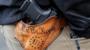 An attendee at a gun rights rally open carries his gun in a holster that reads "We the People" from the Preamble to the United States Constitution, Friday, Jan. 18, 2019, at the Capitol in Olympia, Wash.