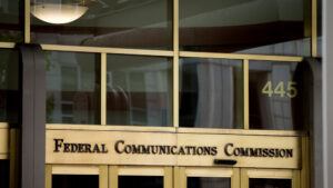 An image of the front of the FCC building, with the full agency name - Federal Communications Commission - appearing above the glass door