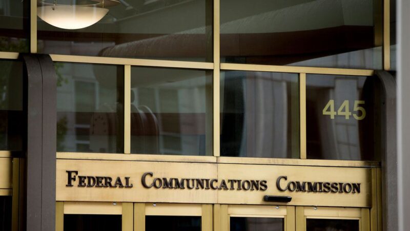 An image of the front of the FCC building, with the full agency name - Federal Communications Commission - appearing above the glass door