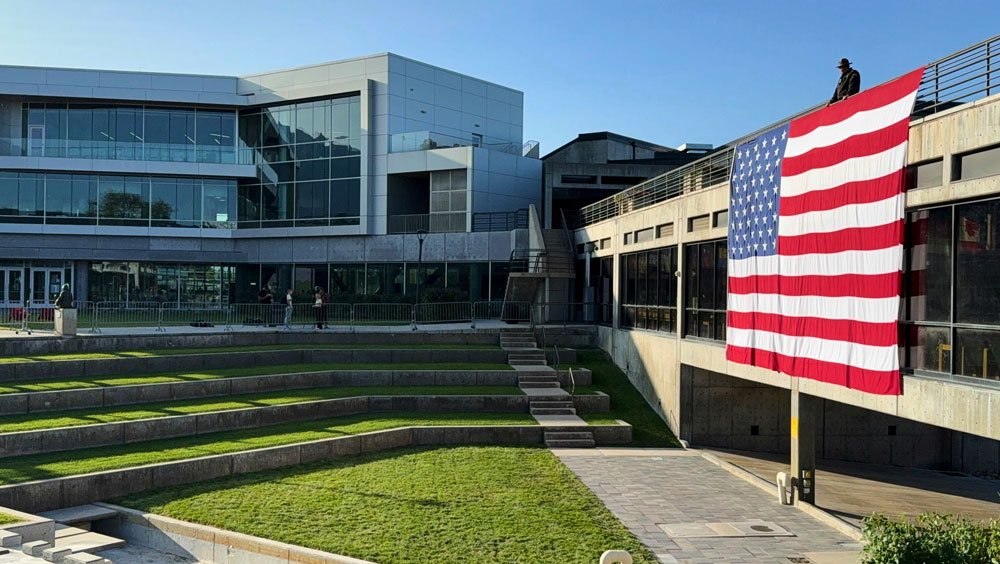 An image of a campus building on the Utah Valley University campus, with a large American flag hanging over the site where Charlie Kirk was killed.