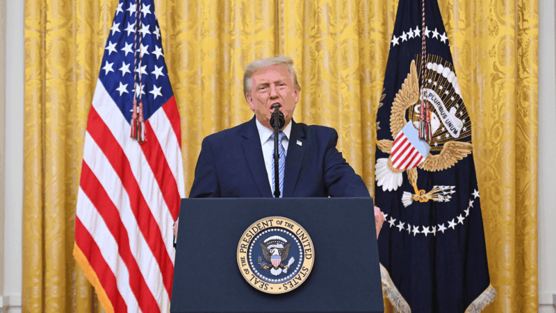 Donald Trump speaks as he stands behind a podium featuring the presidential seal